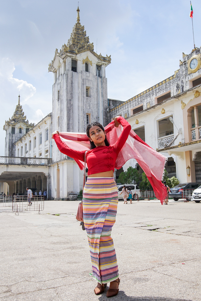 ミャンマー衣装をまとったモデル。ヤンゴン中央駅でスカーフを広げる女性。
