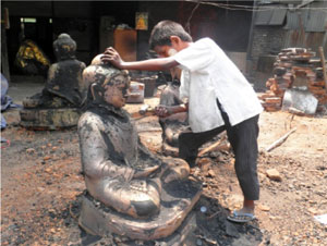 鋳造した仏像のバリ取りをする男の子